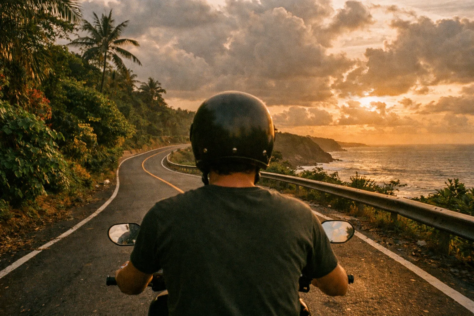 Silhouette of a scooter rider from behind on a winding Bali coastal road at golden hour, rice fields and distant hills in view