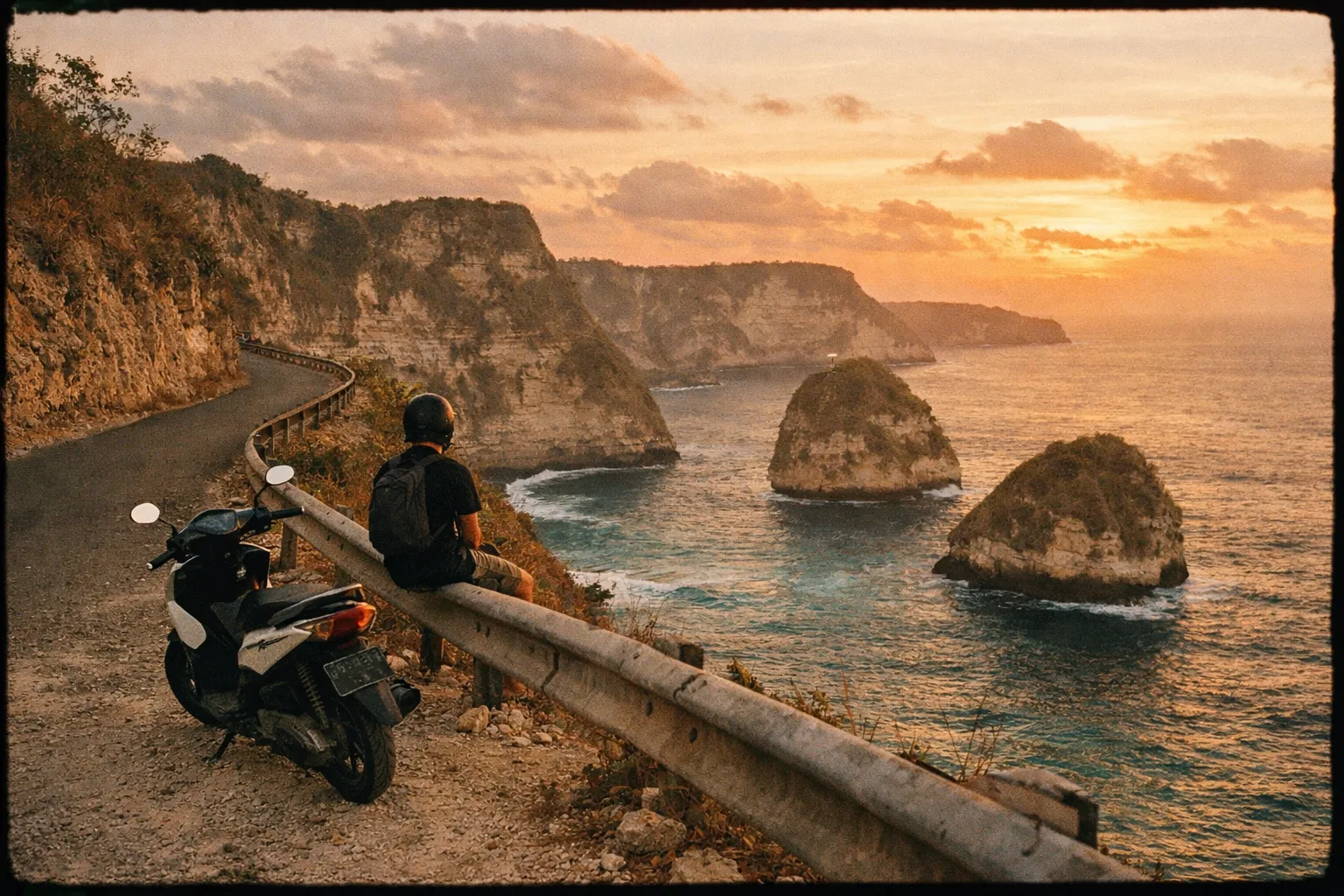 Scooter on a cliff-edge road with turquoise sea and limestone cliffs at sunset