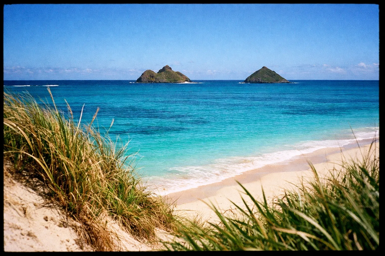 View of Lanikai Beach with turquoise water and the Mokulua Islands in the distance.