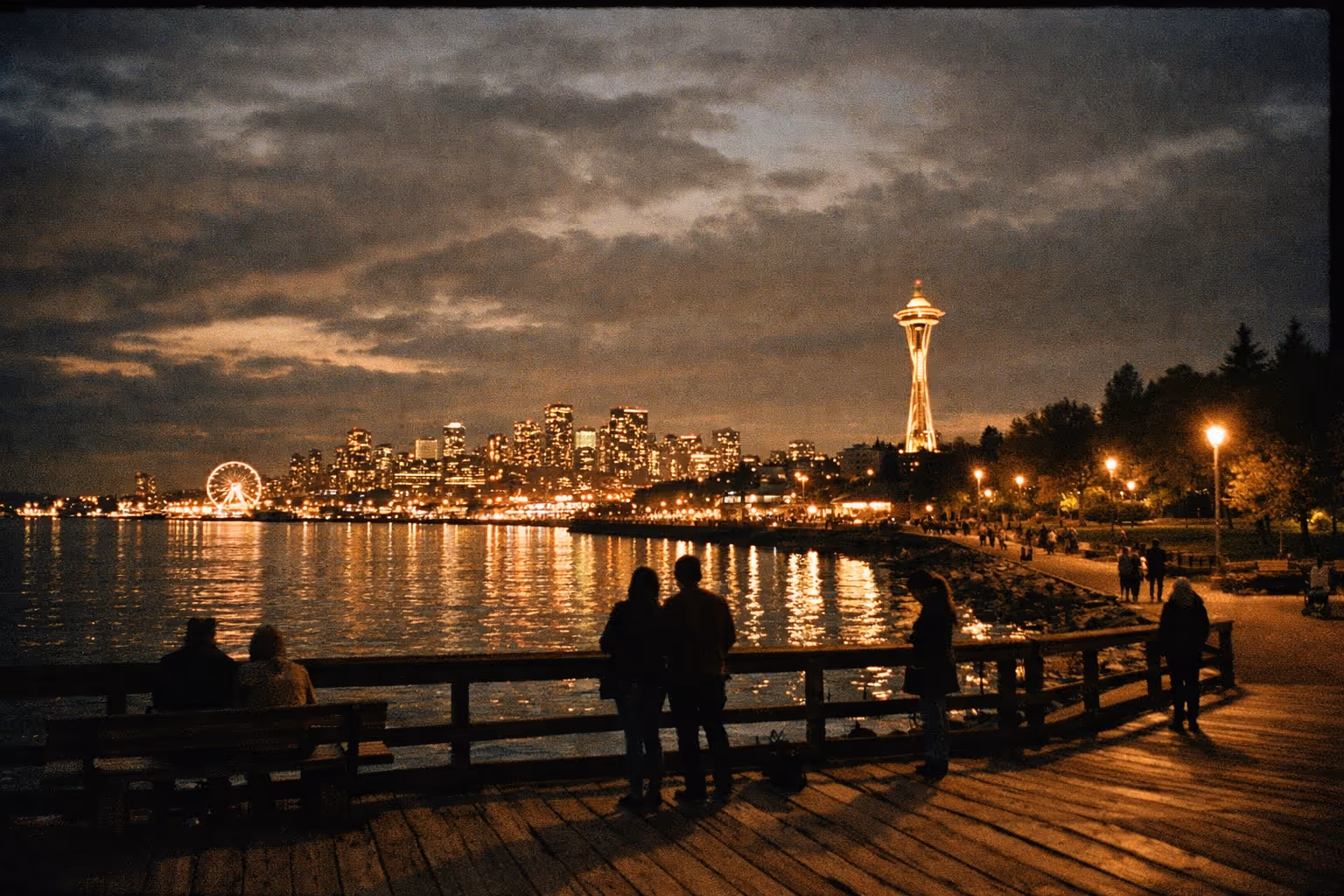Editorial night scene of Seattle with Space Needle in the distance, waterfront, and silhouettes enjoying free city spaces
