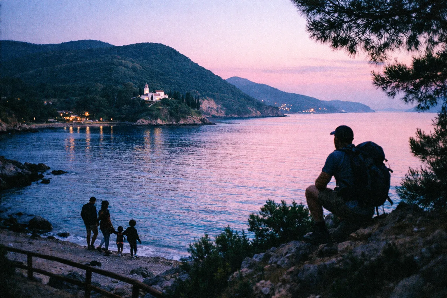 A family and a hiker look at a coastal village with a church on a green Greek island at dusk.