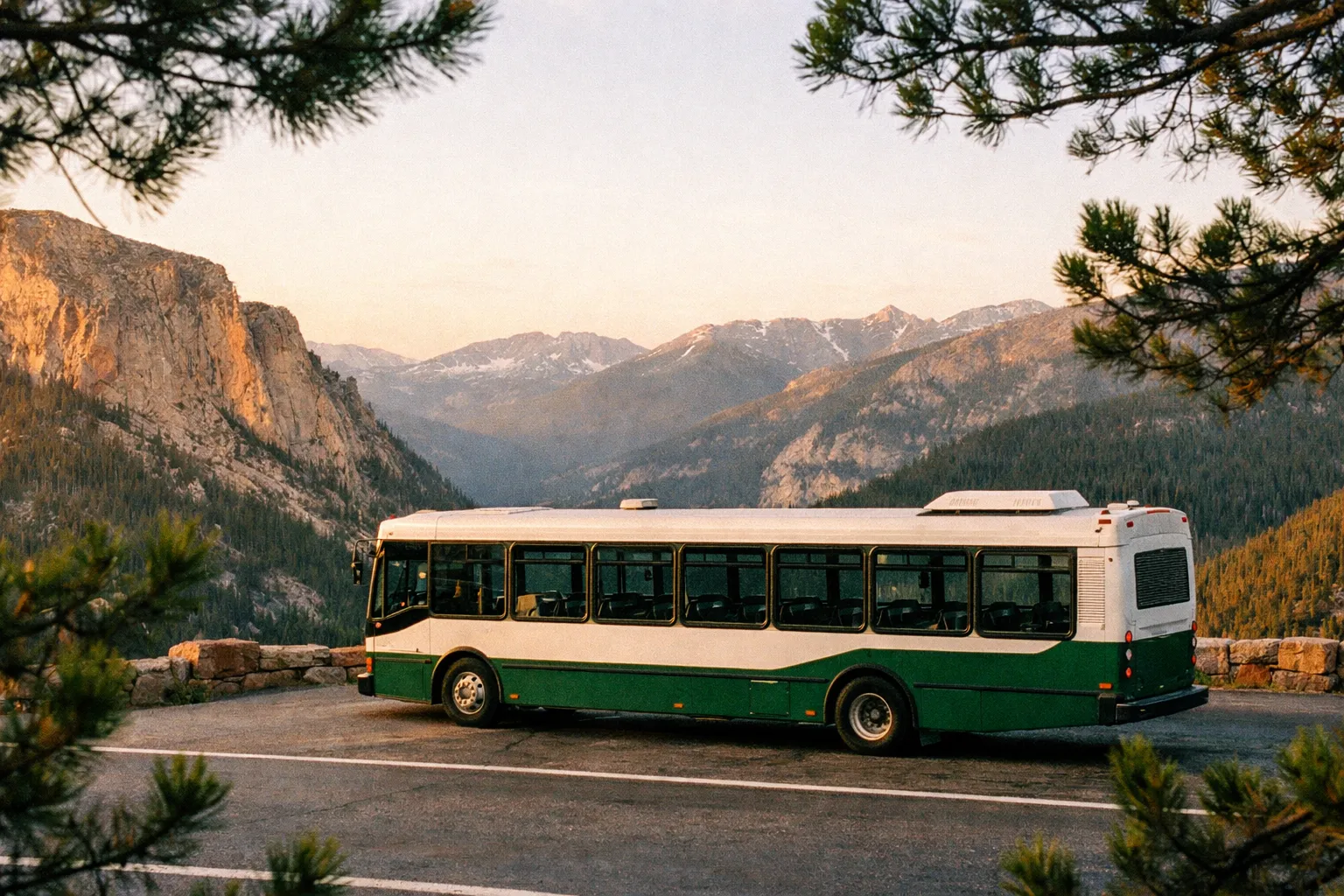 A park shuttle bus is parked at a scenic overlook with pine trees and mountains in the background.