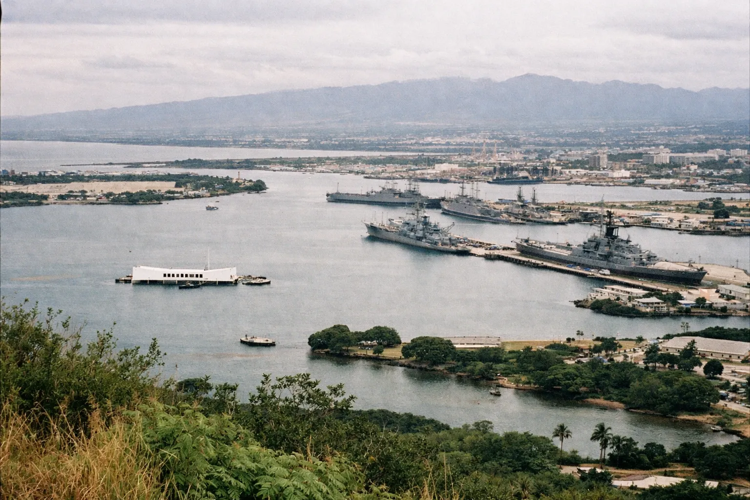 Pearl Harbor with the USS Arizona Memorial and battleships seen from an elevated viewpoint on Oahu, Hawaii.