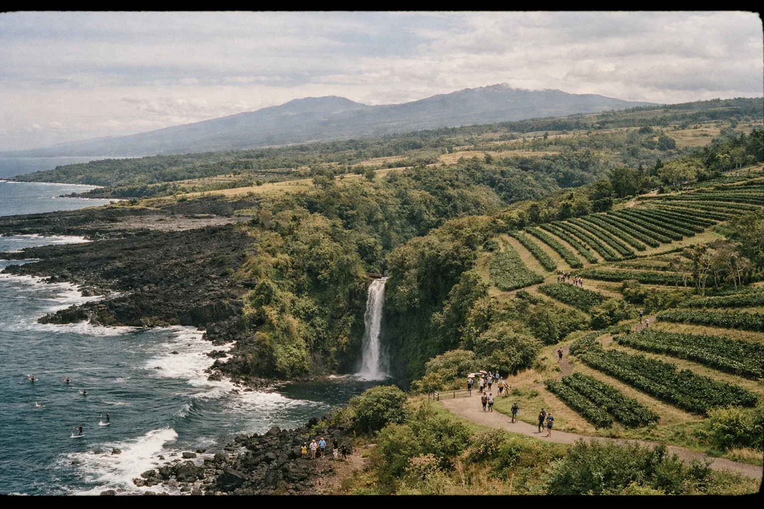 Aerial panorama showing varied Big Island landscapes: volcano, rainforest, coastline, waterfall, and fields