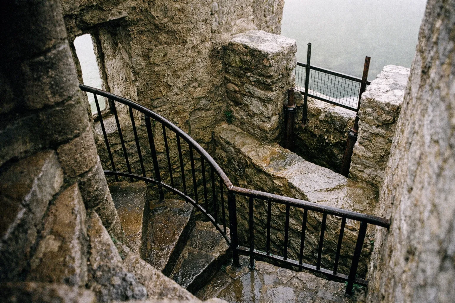 A winding stone staircase with iron railings inside the ruins of Blarney Castle.
