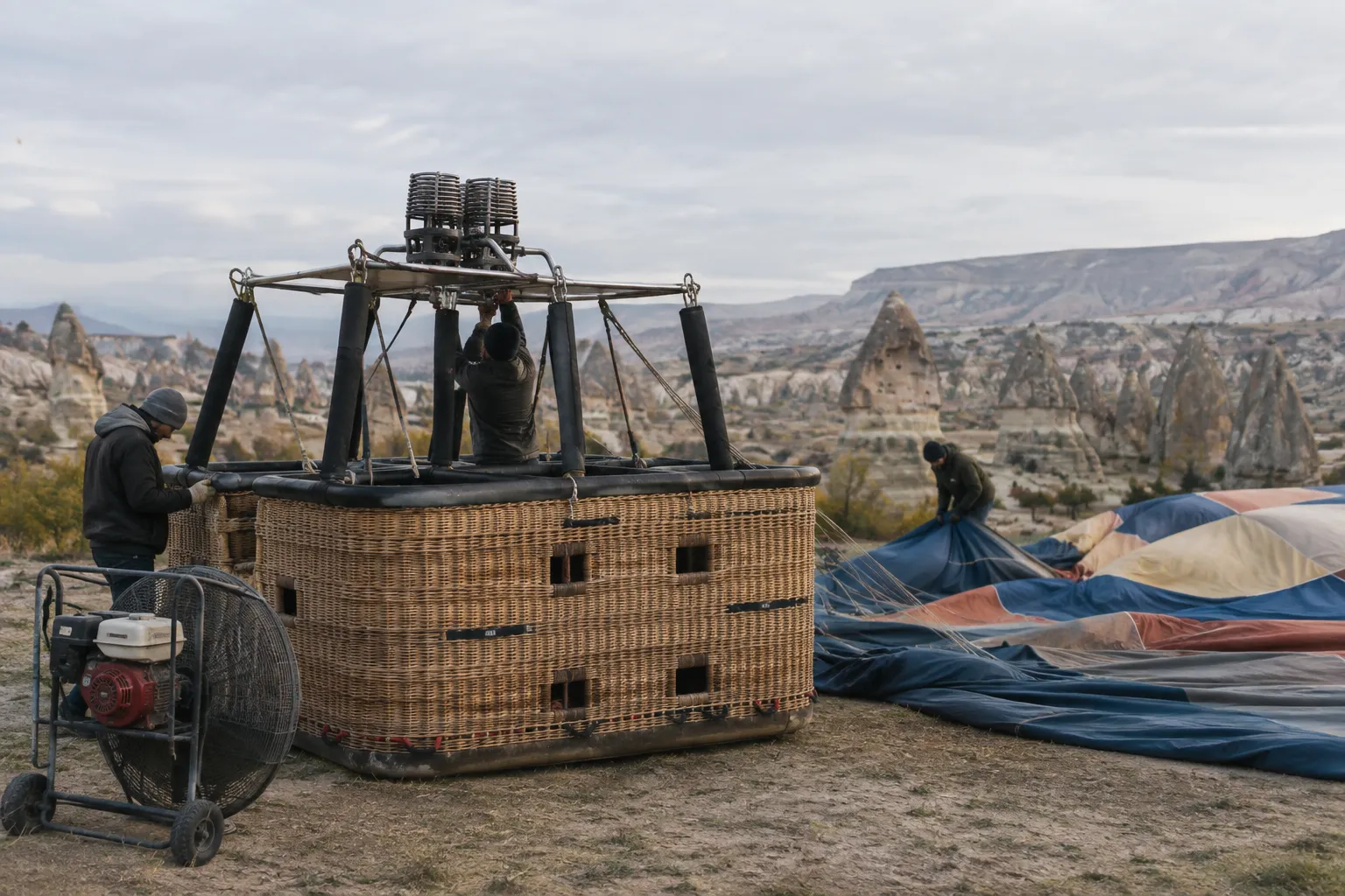 Workers prepare a hot air balloon in Cappadocia's rocky valley.