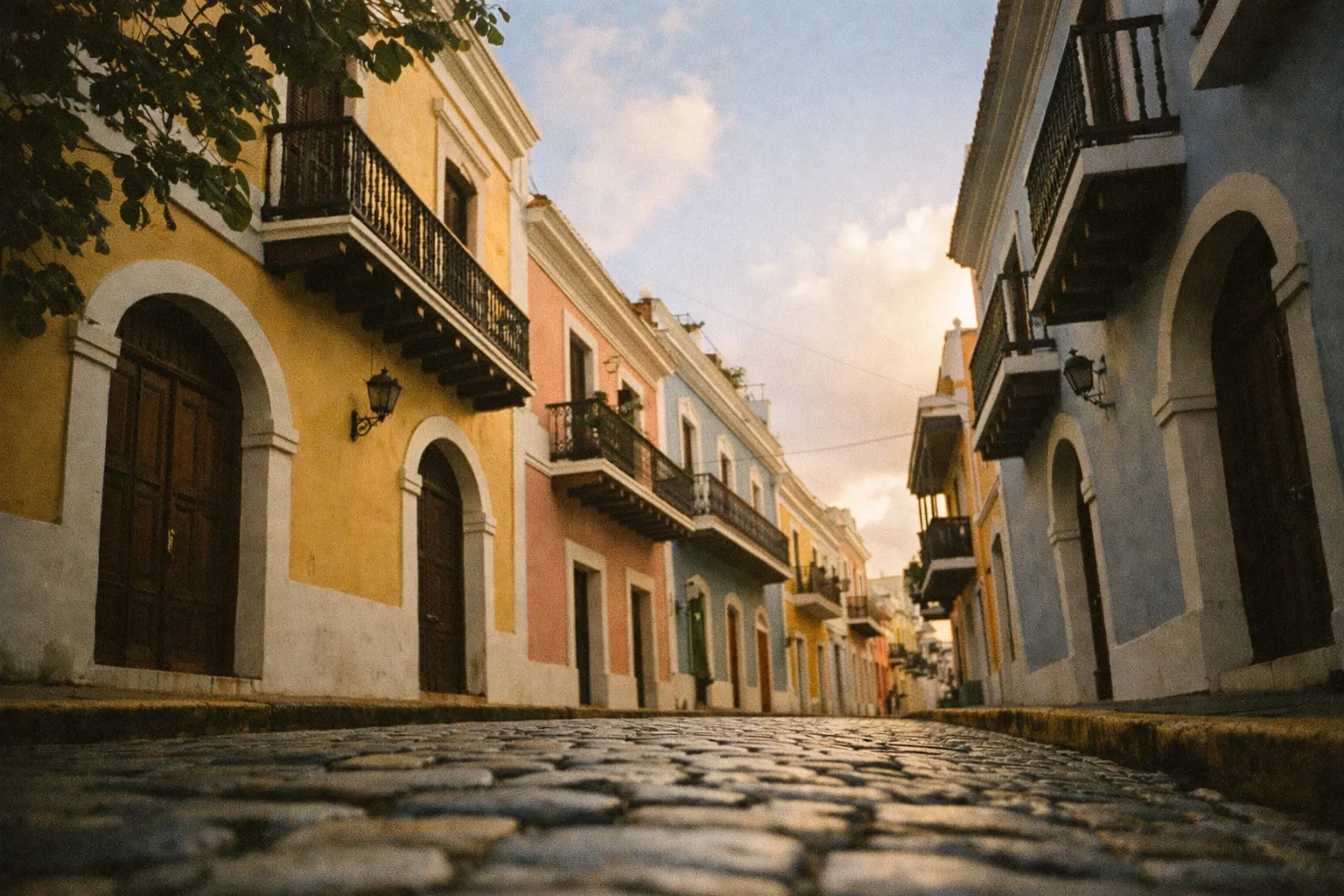 Colorful colonial buildings line a cobblestone street in Old San Juan, Puerto Rico at sunset.