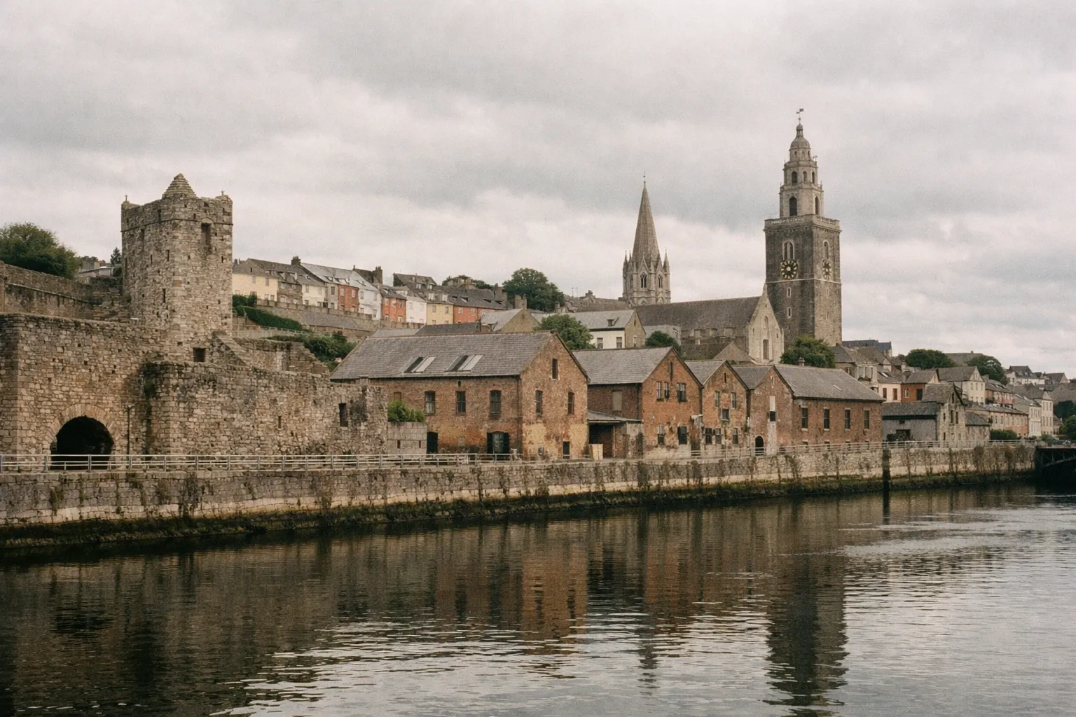 Shandon Tower and old stone buildings line the riverbank in Cork, Ireland.