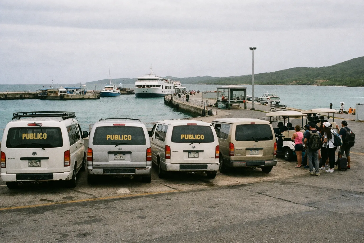 Vans labeled 'Publico' parked near a ferry dock as people wait by the waterfront in Culebra, Puerto Rico.
