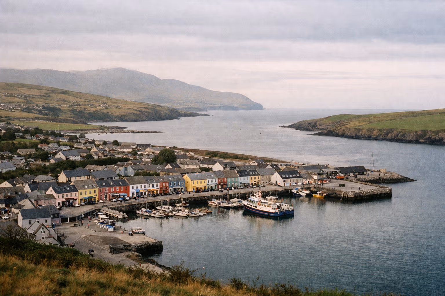 Colorful buildings and boats line the harbor in the coastal town of Dingle, Ireland.