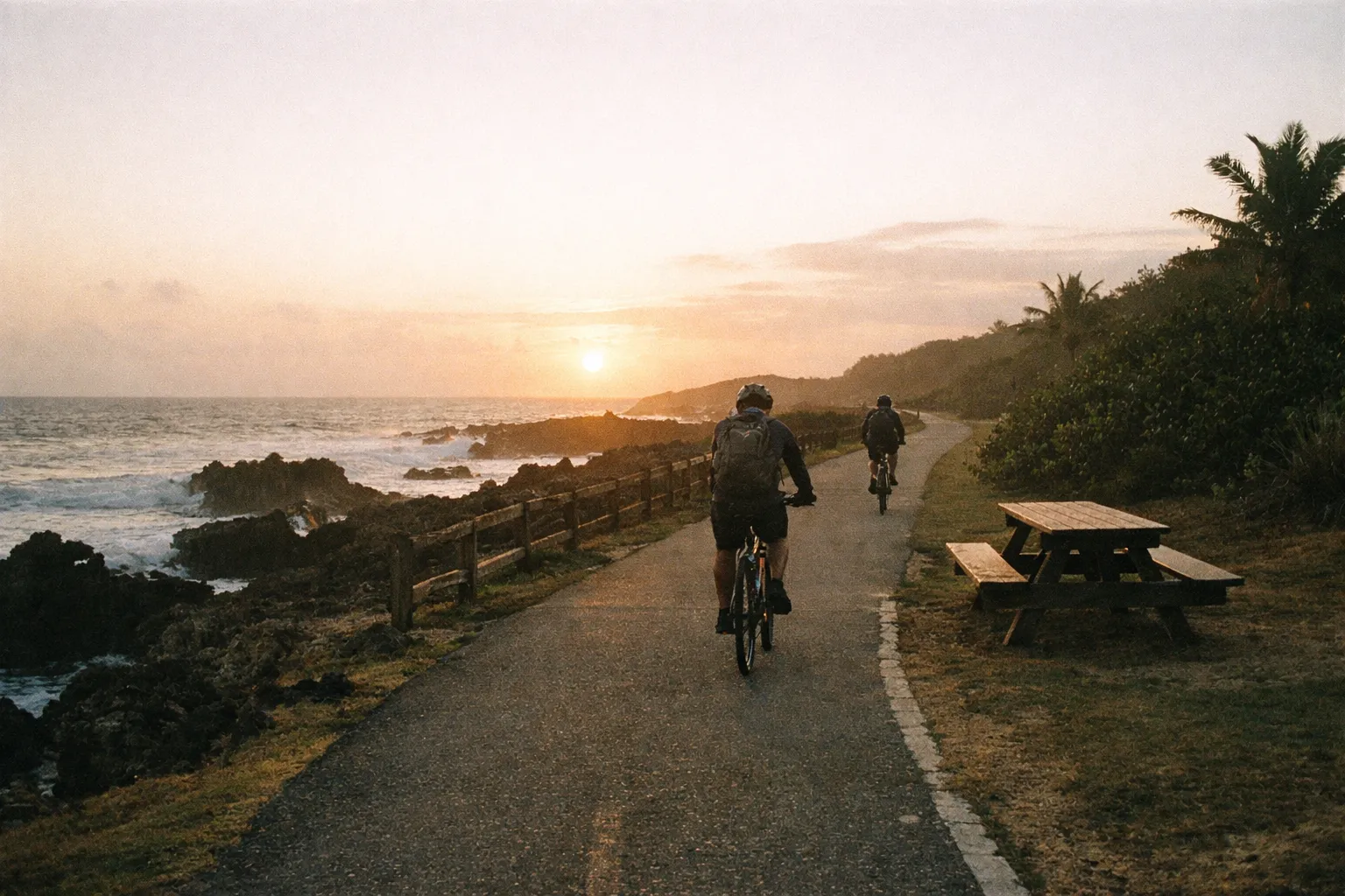 Early morning along the Paseo Lineal de Isabela with the coastal trail, lava-rock coves, and cyclists seen from behind