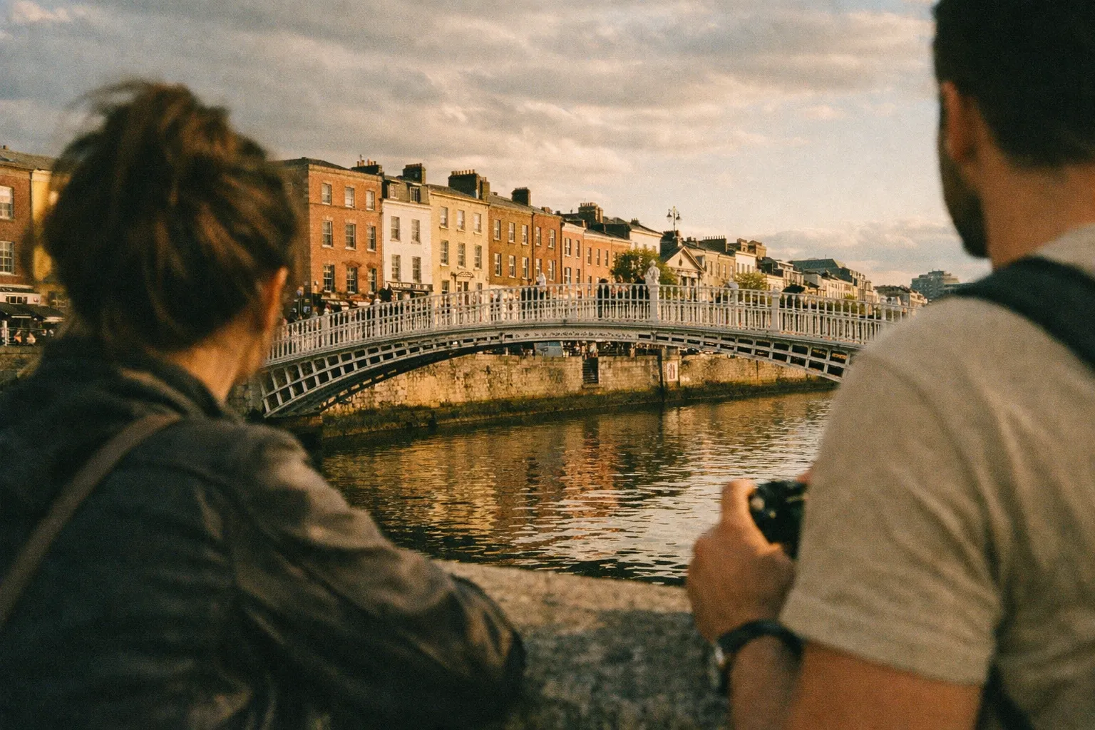 Two people look towards the Ha'penny Bridge over the River Liffey in central Dublin.