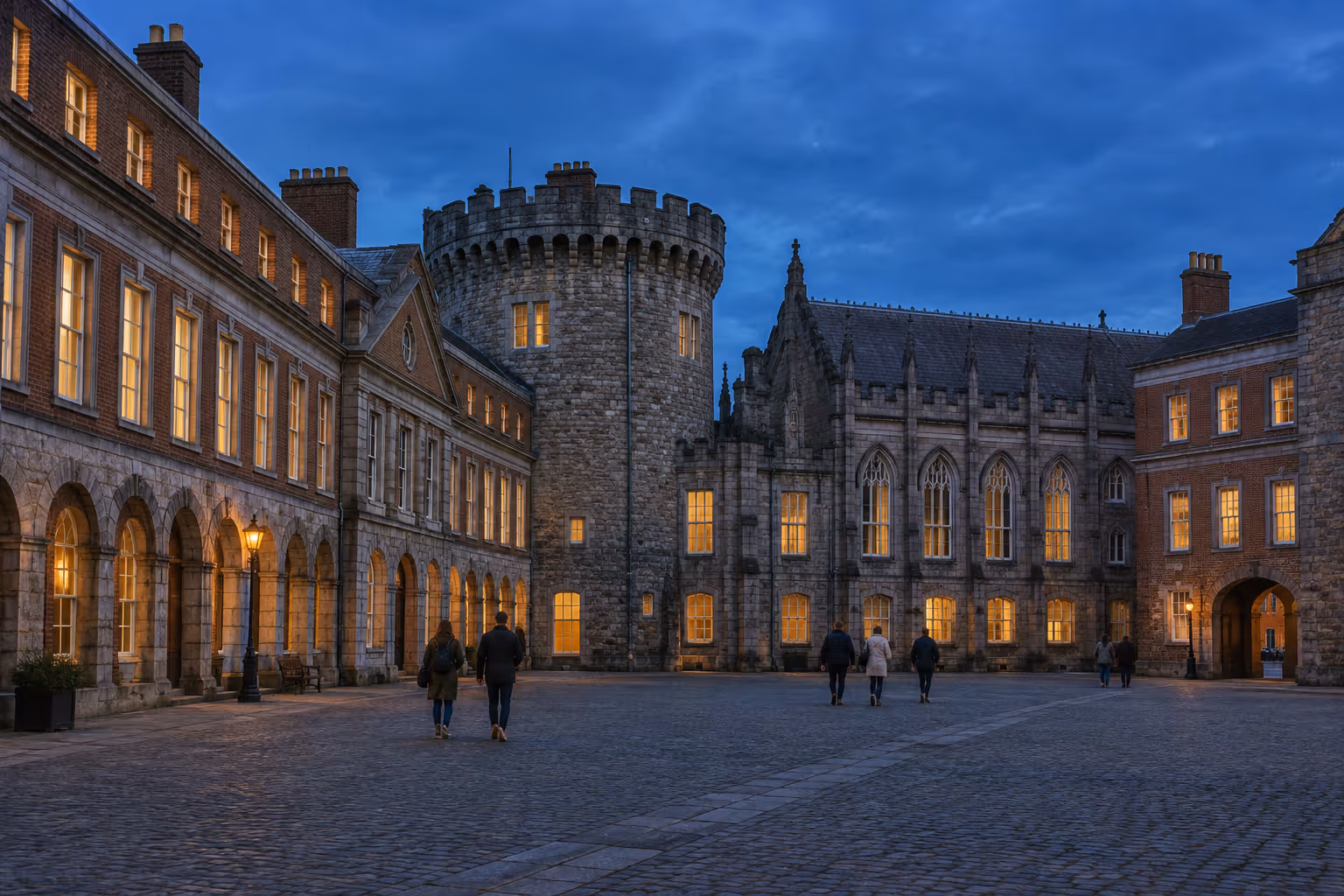 Dublin Castle's courtyard is lined with historic stone buildings at dusk.