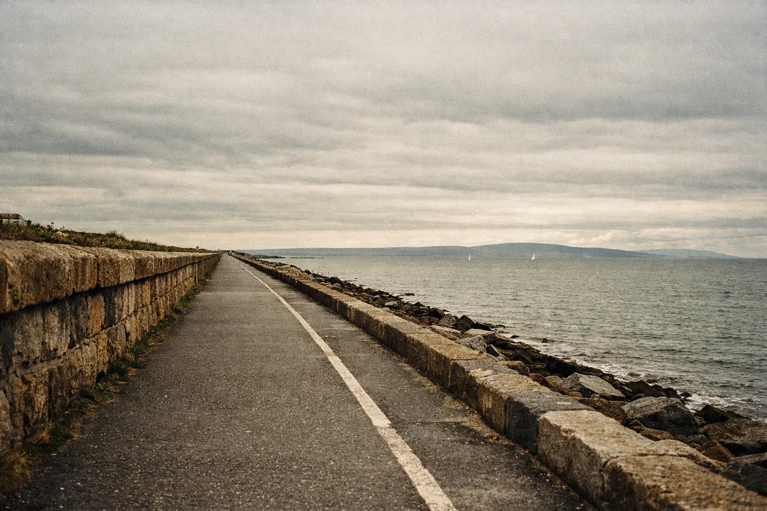 The Salthill Promenade runs along the Galway Bay shoreline under a cloudy sky.
