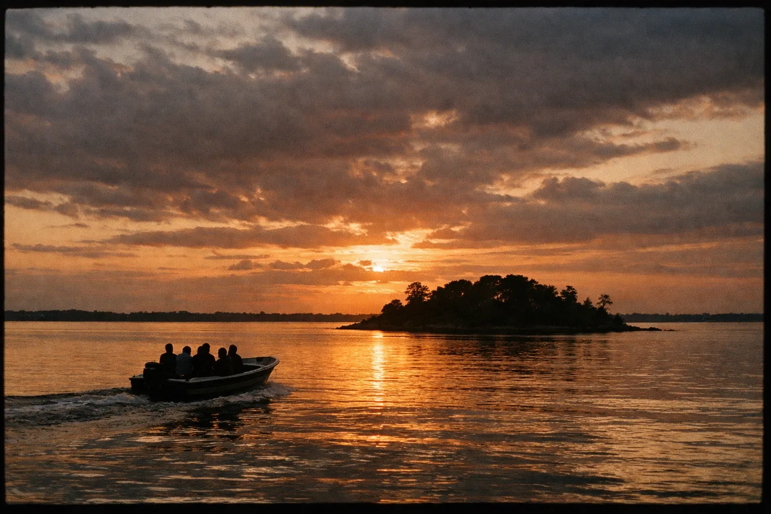 Small motorboat crossing calm water toward Samsons Island at golden hour