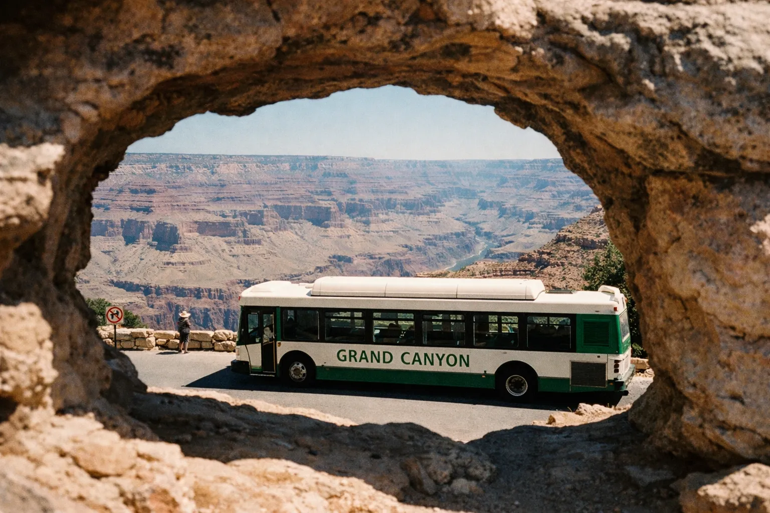 A Grand Canyon shuttle bus parked at a scenic overlook with canyon views in the background.