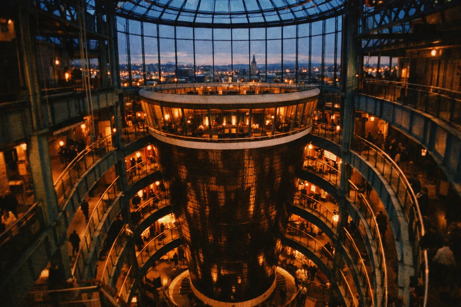 People walk inside the multi-level atrium of the Guinness Storehouse in Dublin at dusk.