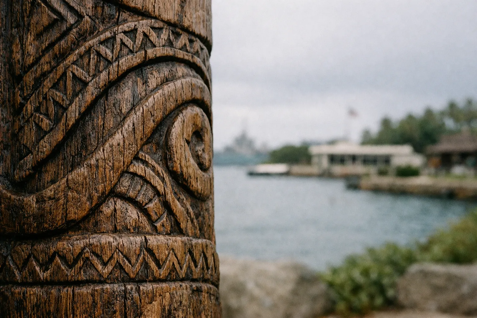 Close up of a carved wooden post with water and buildings in the blurred background