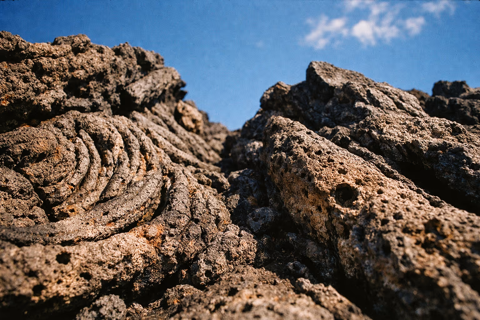 Close-up view of rugged volcanic lava rock under a clear blue sky in Hawaii Volcanoes National Park.