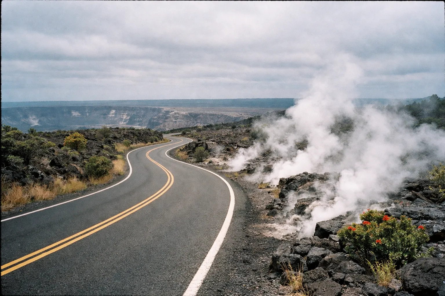 A winding road passes steaming volcanic vents and rugged lava rocks at Hawaii Volcanoes National Park.