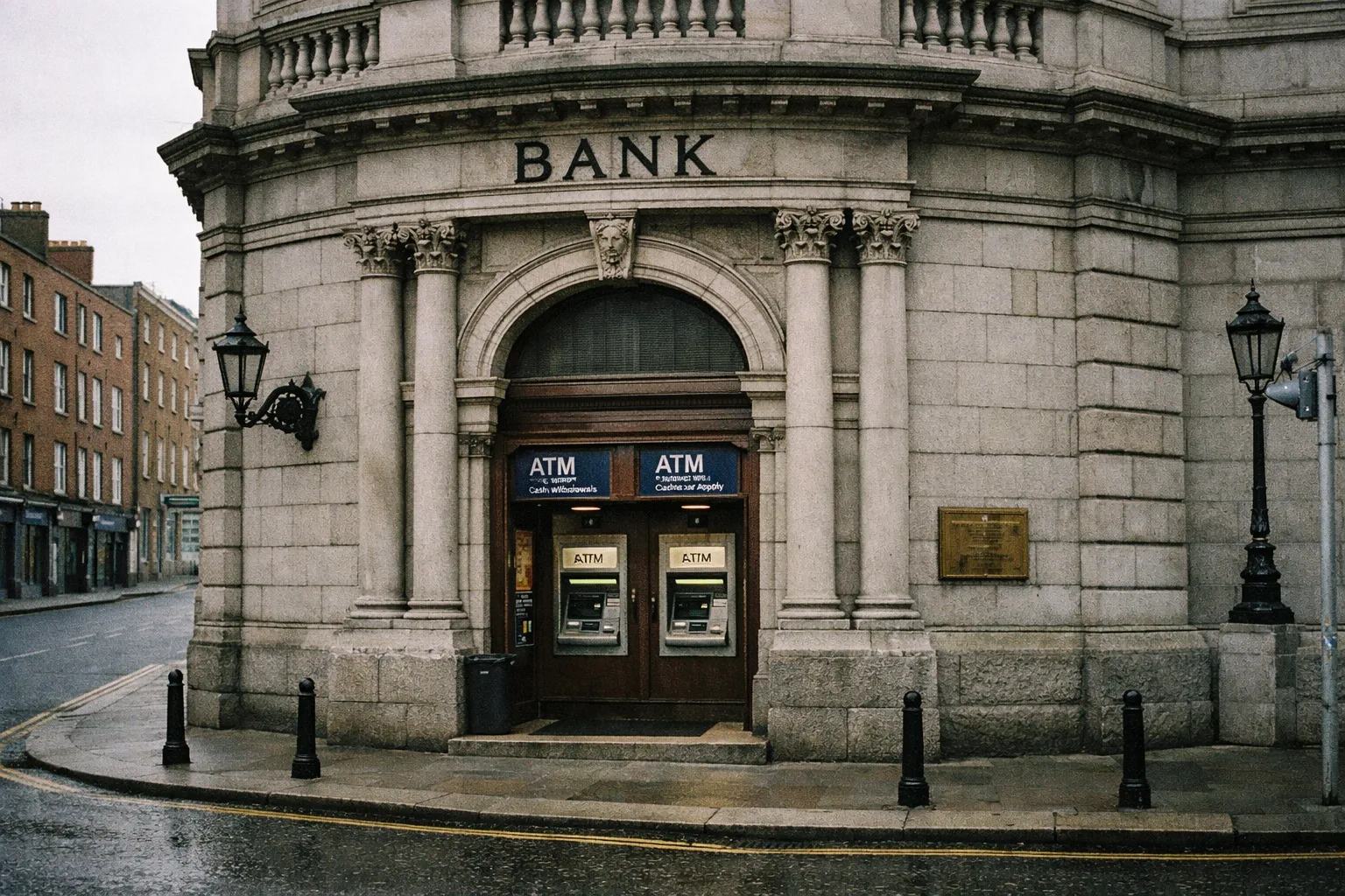 Bank building with two ATMs on a wet city street corner in Ireland.