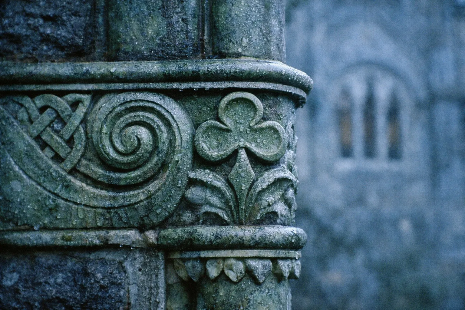 Close-up of a weathered stone column with Celtic carvings on the estate.