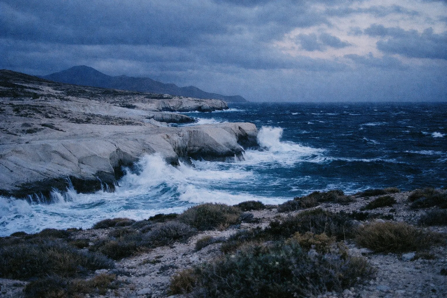 Waves crash against the white rocky cliffs of Sarakiniko Beach on the island of Milos, Greece.