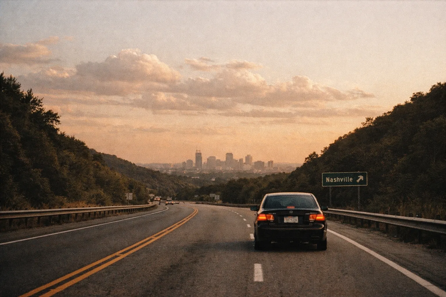 Approaching Nashville on a scenic highway with the city skyline at sunset