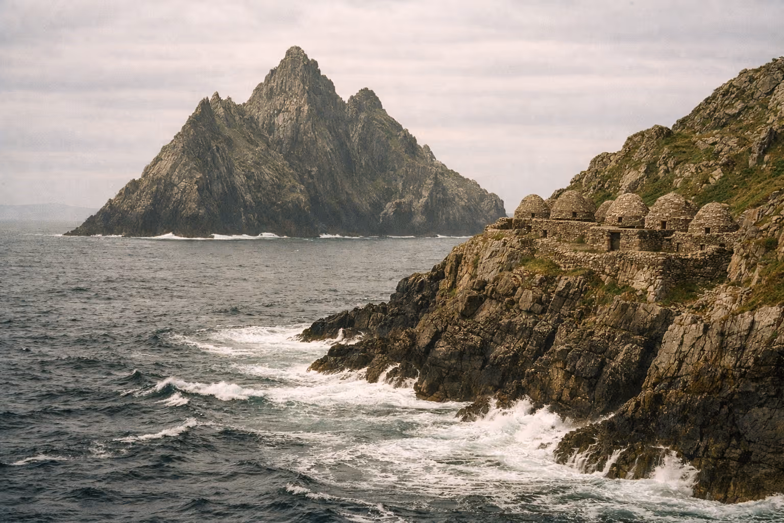 Stone beehive huts sit on the rocky cliffs of Skellig Michael above the Atlantic Ocean.