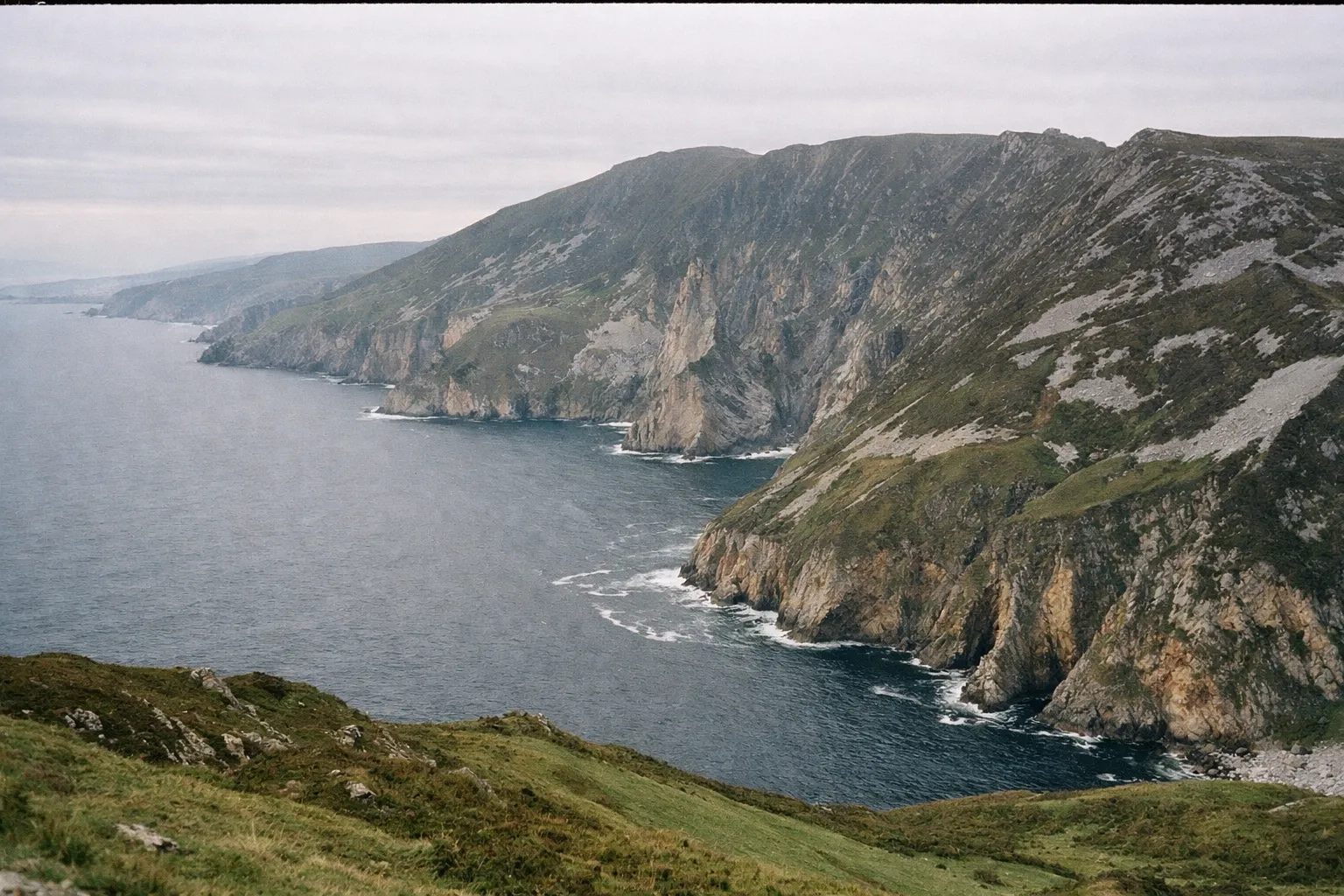 Sheer cliffs of Slieve League rise above the Atlantic Ocean along a rugged coastline.
