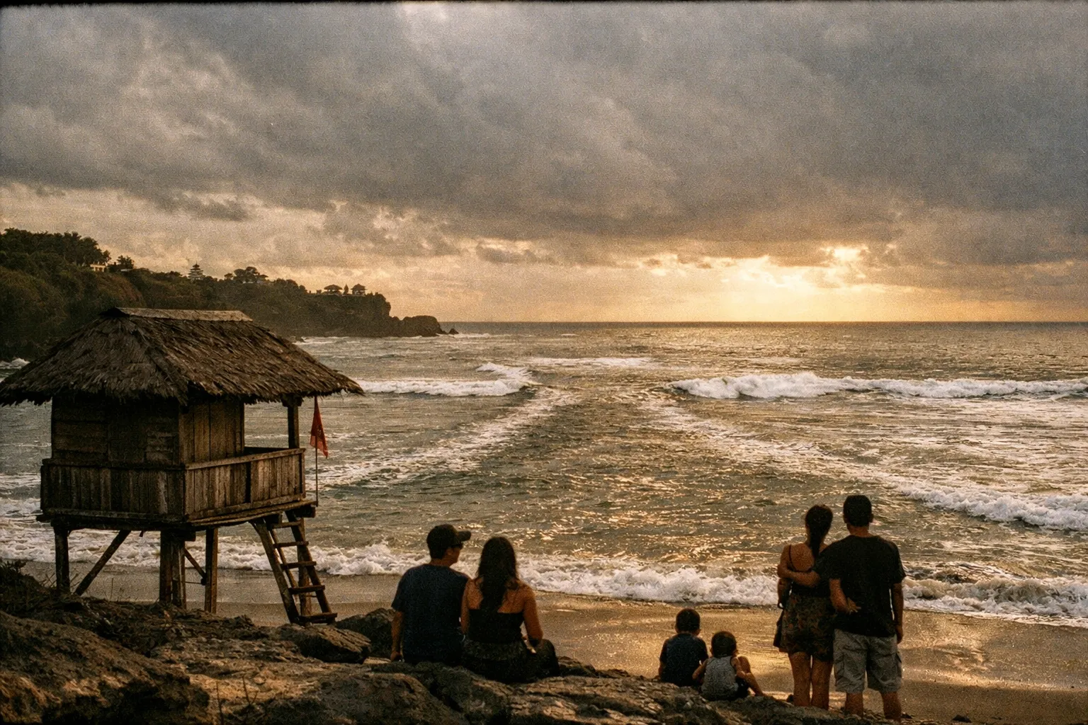 Rip current awareness along Bali coast at golden hour, rugged shoreline with a visible water channel, silhouettes of beachgoers from behind