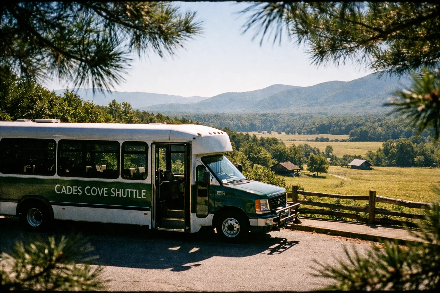 Cades Cove shuttle bus parked by a scenic overlook in the Great Smoky Mountains with mountains and fields visible.