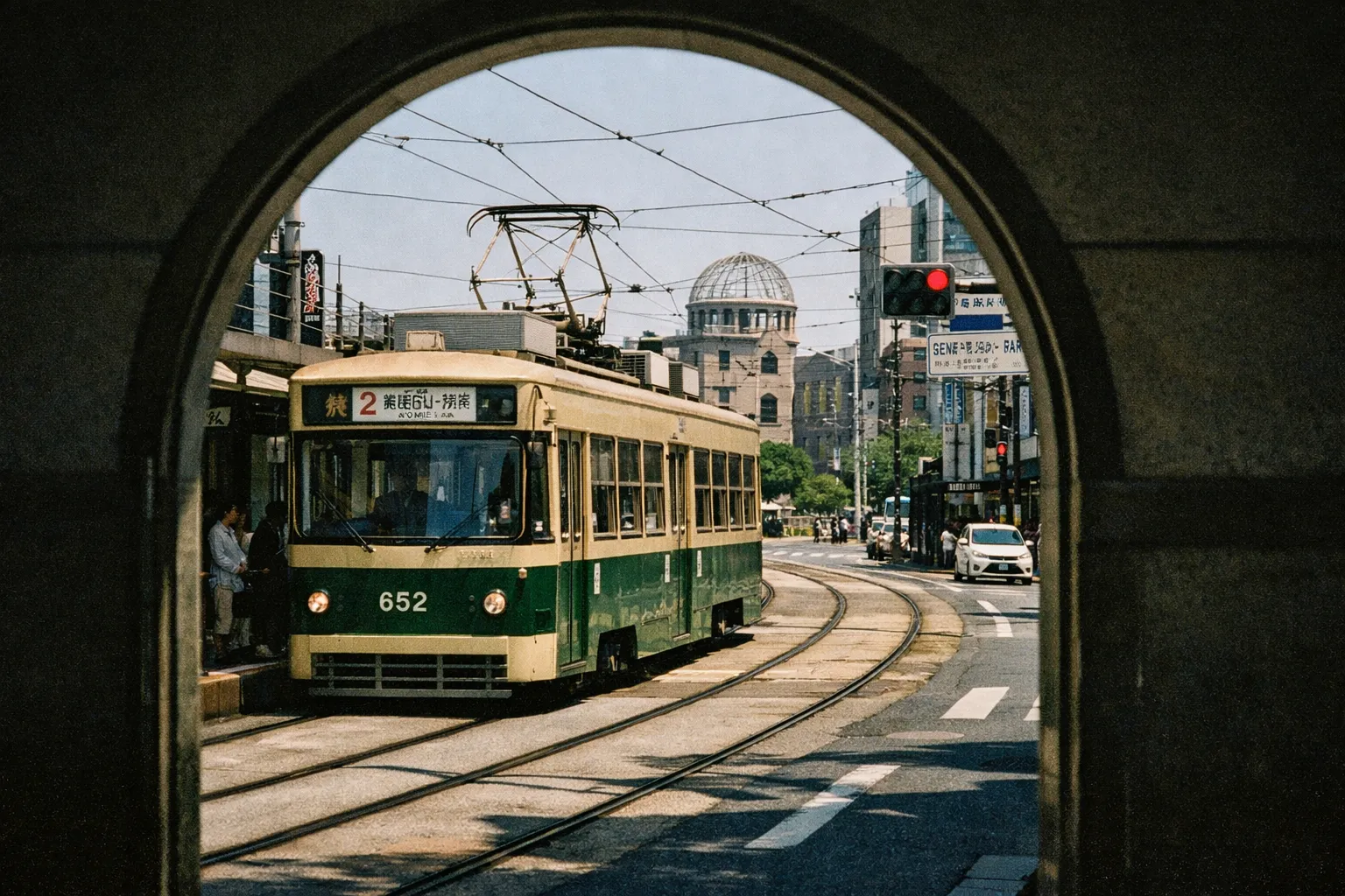 A streetcar passes in front of the Hiroshima Peace Memorial Dome in an urban setting.