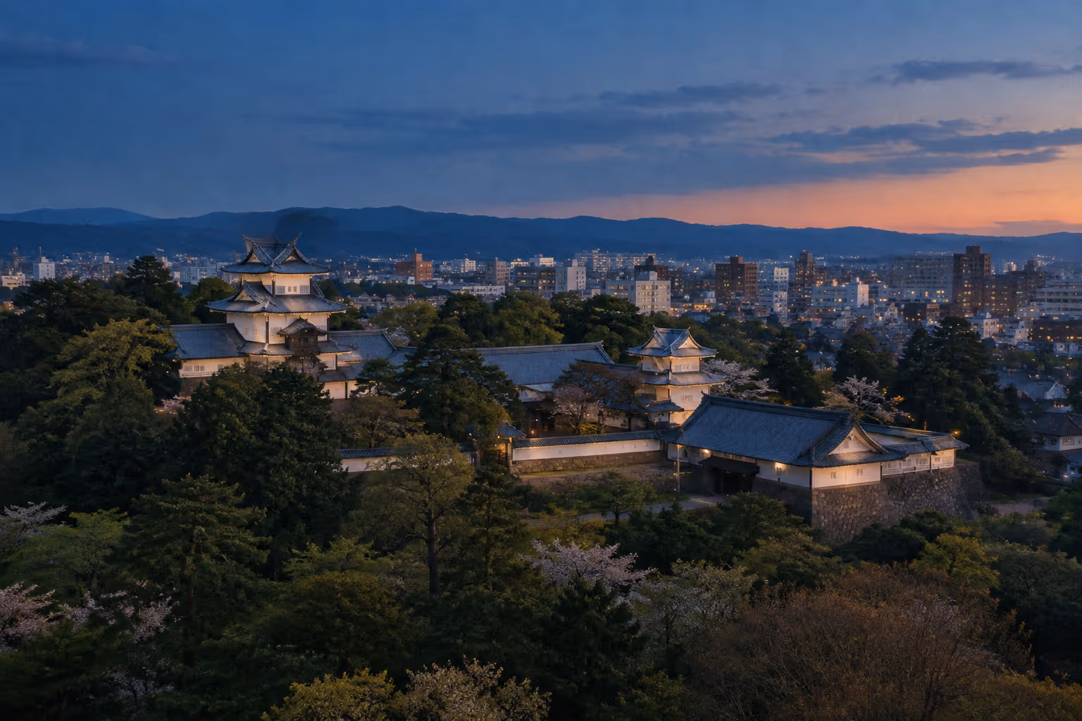 Kanazawa Castle stands among trees above the city at sunset.