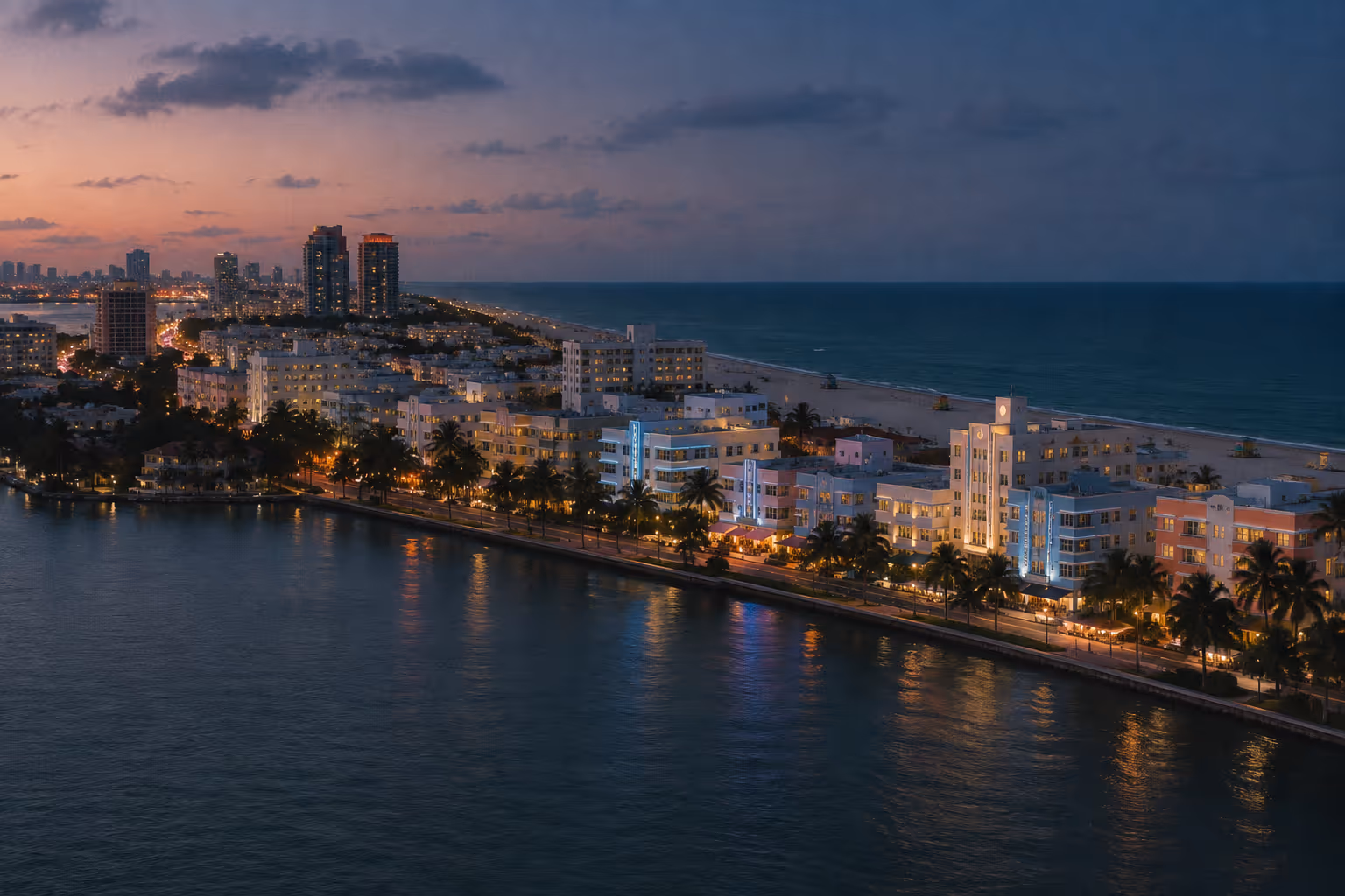 Miami Beach's shoreline and waterfront buildings glow at dusk beside the ocean.