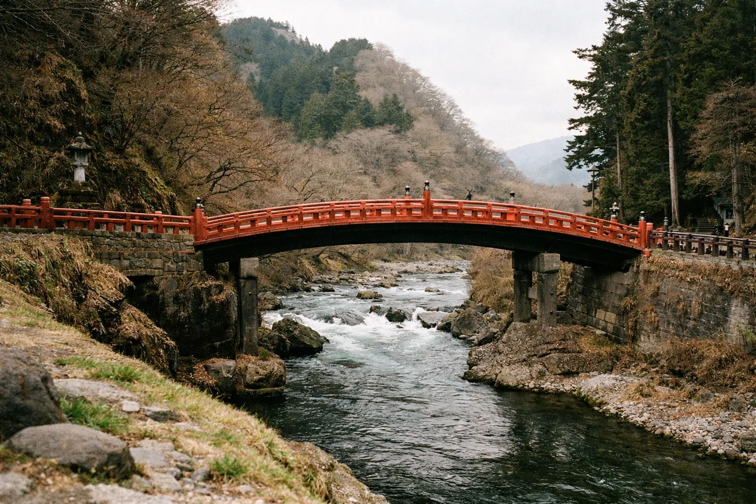 The Shinkyo Bridge arches over a river surrounded by forested hills in Nikko, Japan.