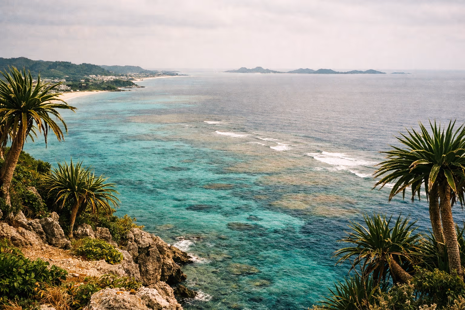 Rocky coastline with turquoise water and lush greenery along the shore in Okinawa, Japan.