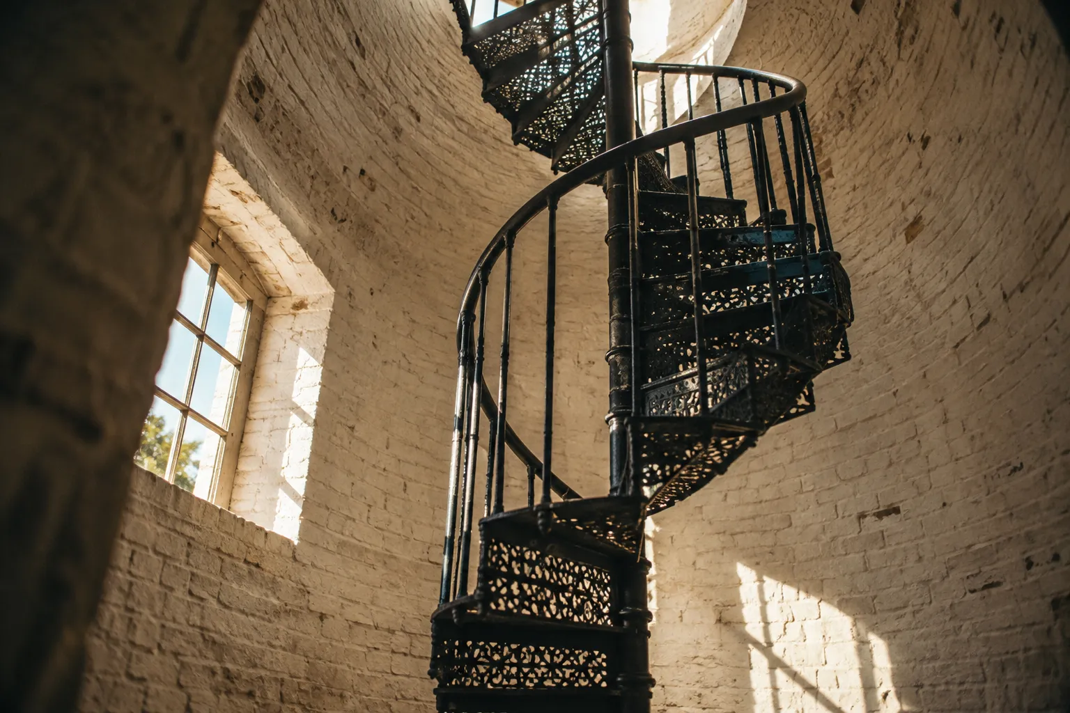 A black spiral staircase rises inside the brick tower of the St. Augustine Lighthouse.