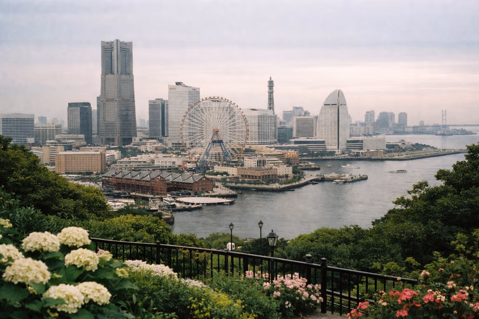 The Yokohama waterfront skyline with the Cosmo Clock 21 Ferris wheel and Minato Mirai seen from a garden overlook.