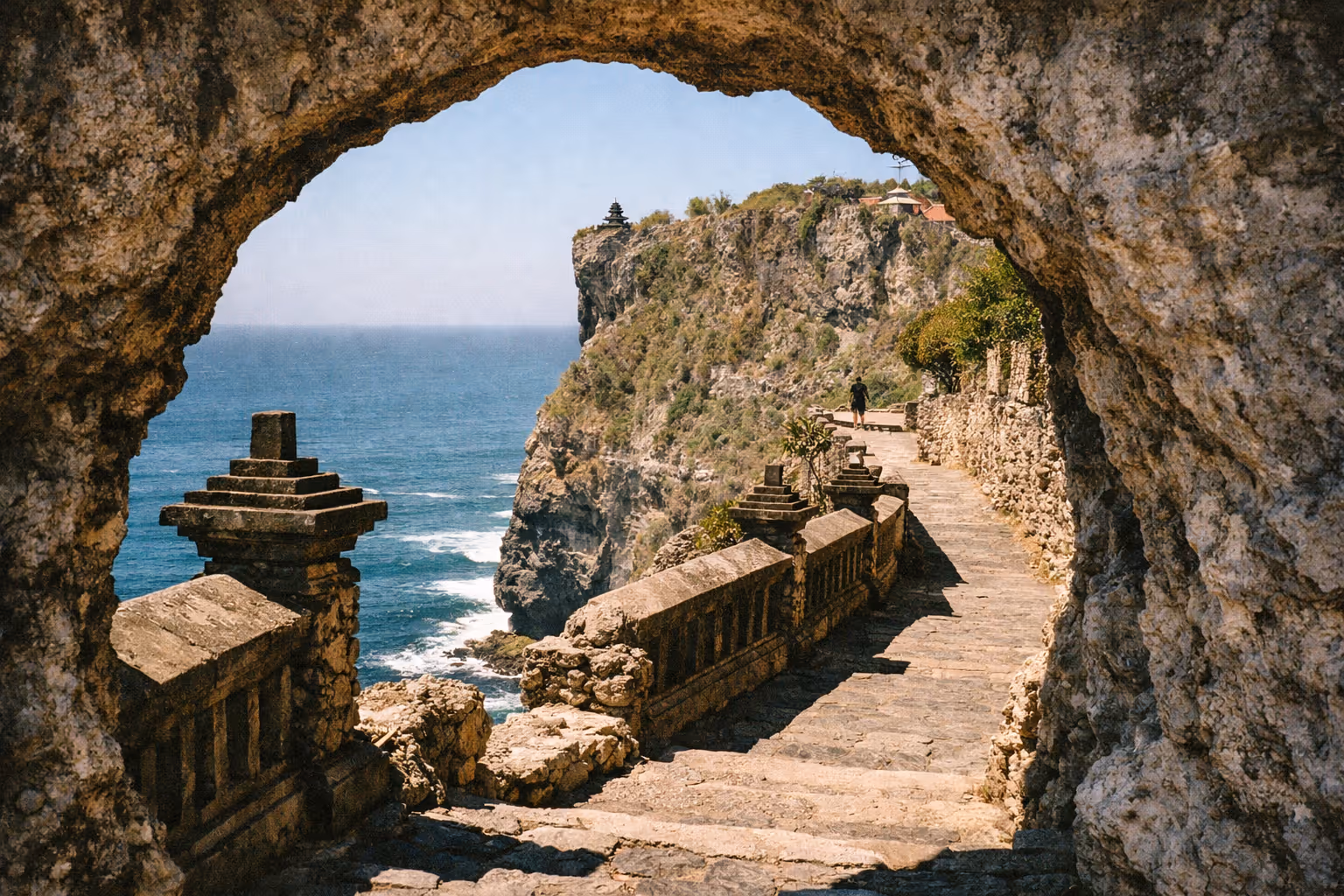 Stone pathway and railing along the cliff at Uluwatu Temple overlooking the sea in Bali.