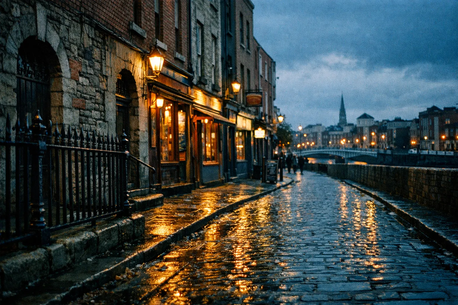 Wet cobblestone street with old buildings, iron fence, and warm streetlights on a cloudy evening