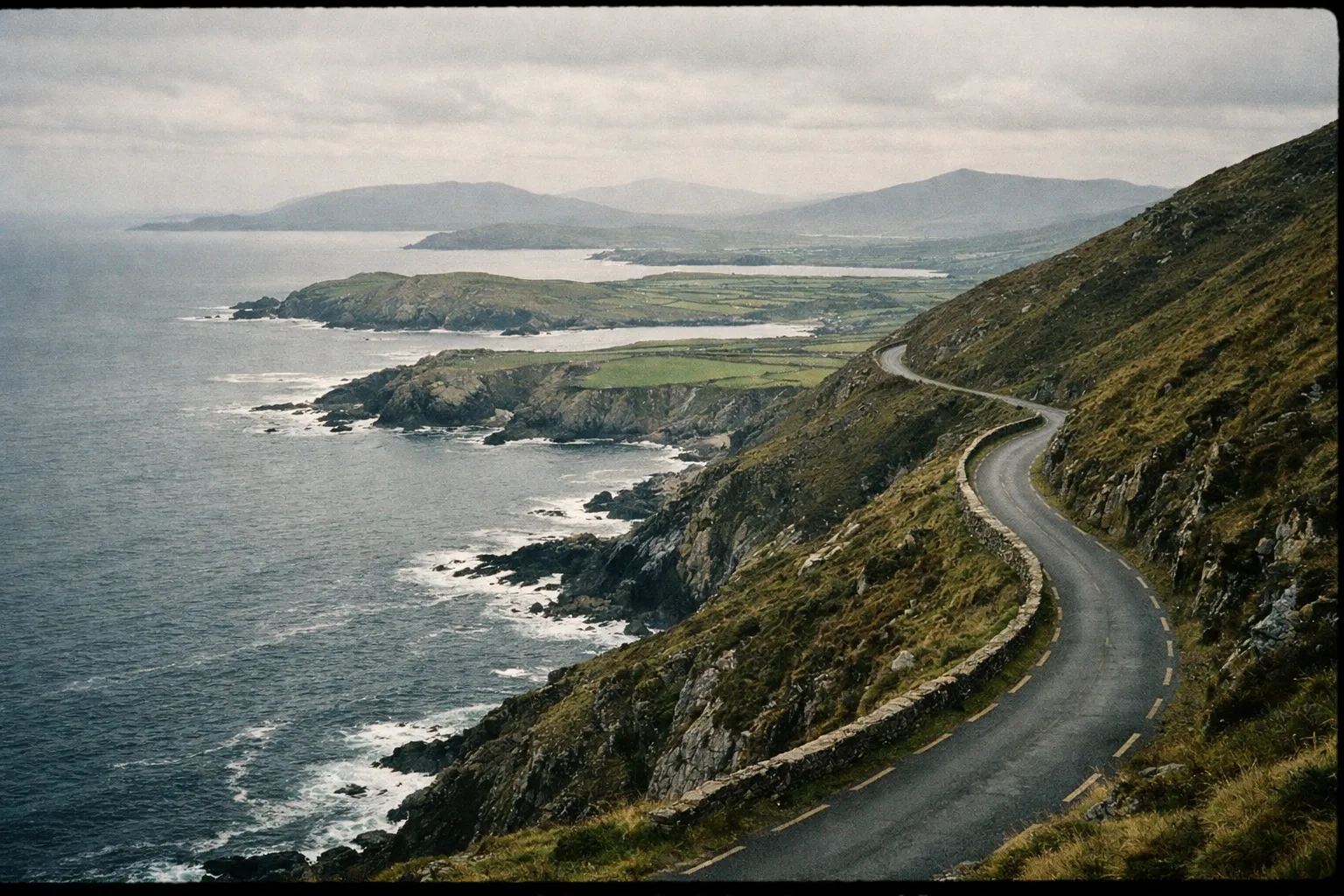 A winding coastal road hugs steep cliffs above the Atlantic Ocean on Ireland's Wild Atlantic Way.